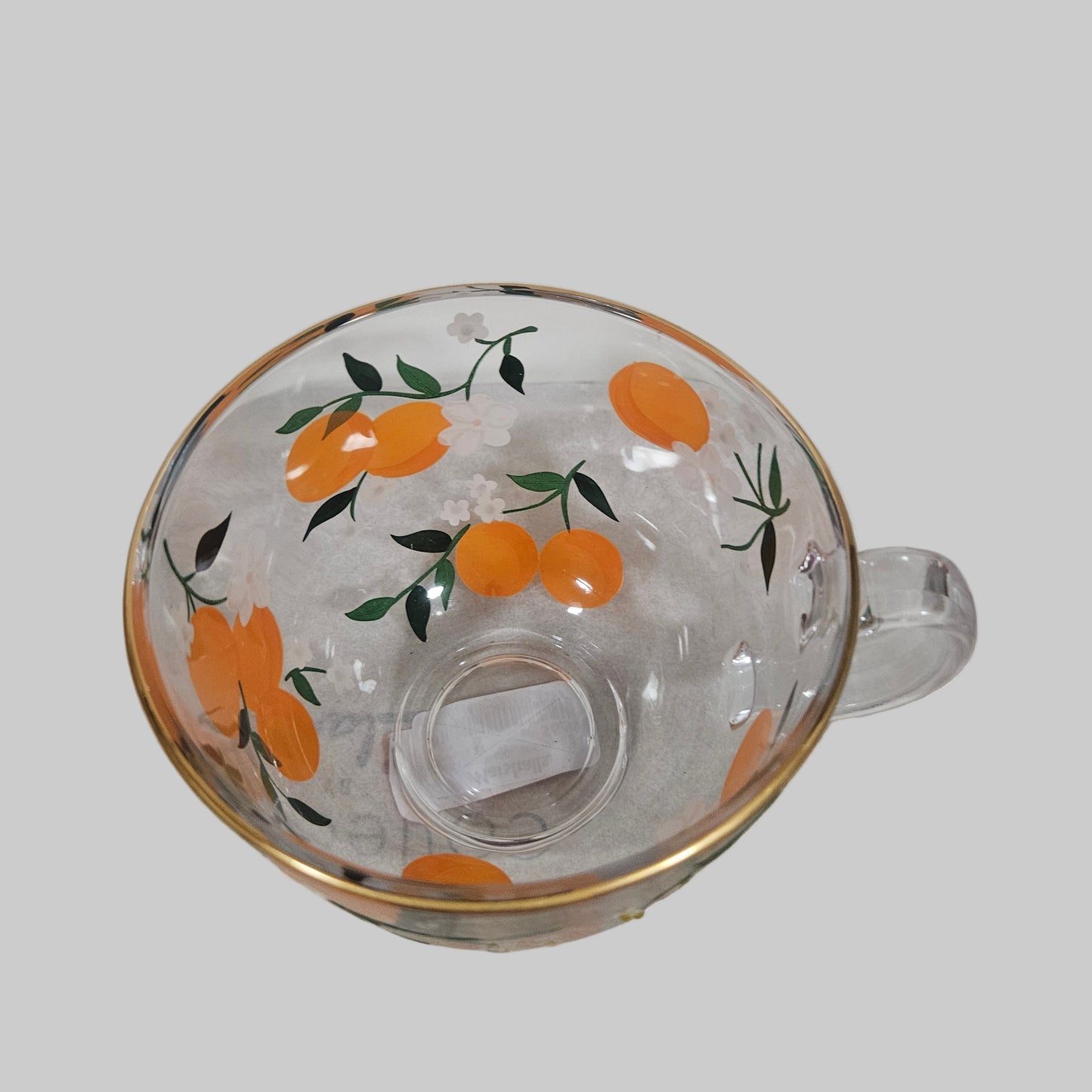 Clear glass mug with orange fruit design on a white background
