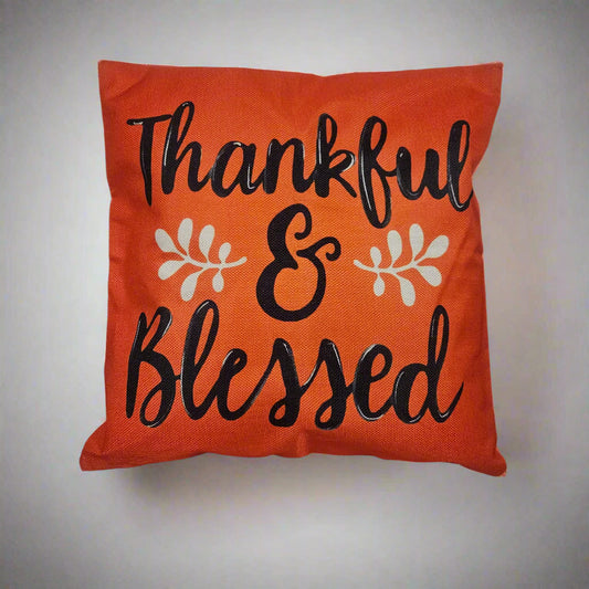 Orange pillow with 'Thankful & Blessed' text on a white surface